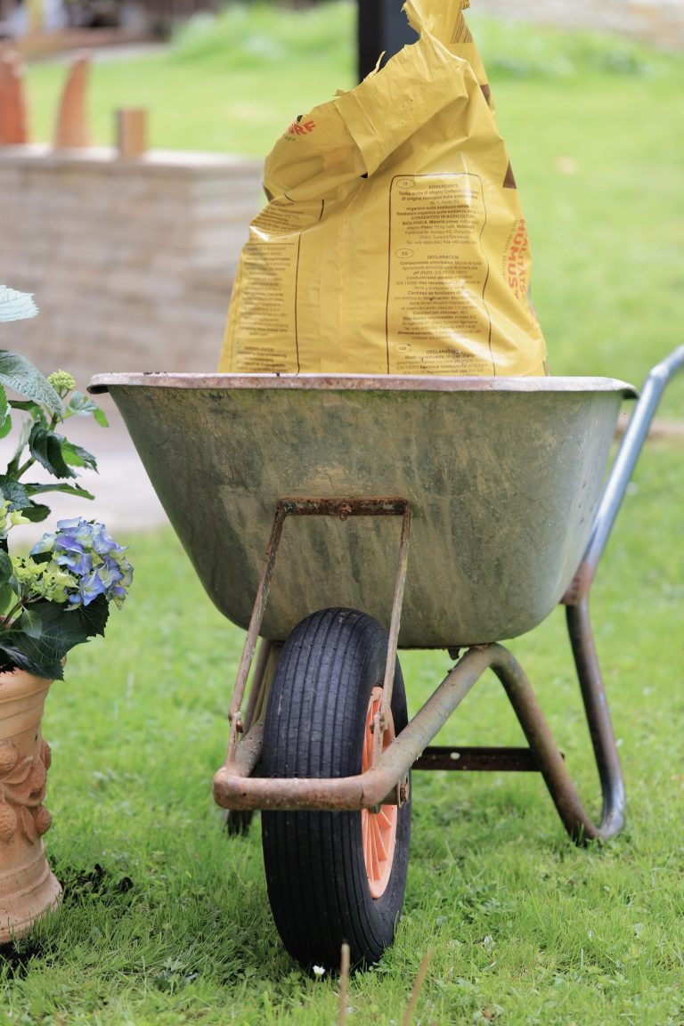 Kruiwagen met een zak potgrond in de tuin